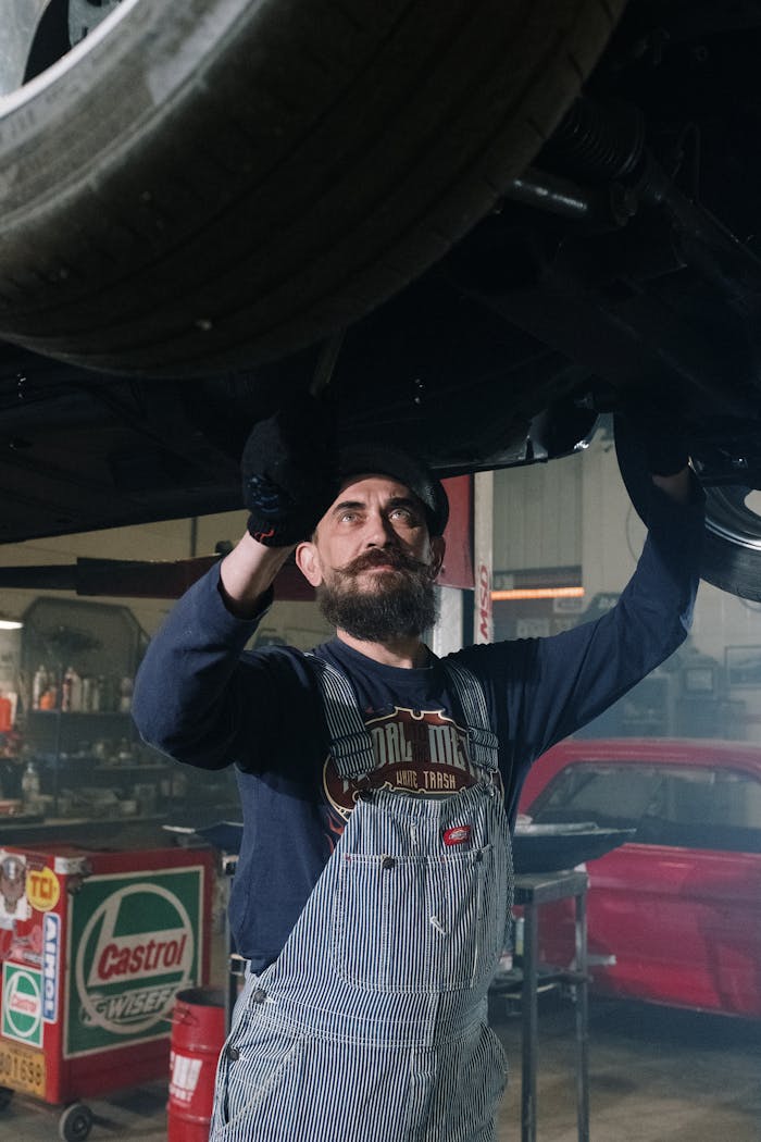 Dedicated mechanic with a mustache repairs a vehicle indoors, showcasing automotive expertise.
